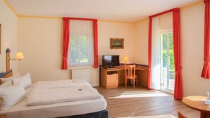 Habitación de hotel con cama, escritorio, silla, televisor y ventana con cortinas.
