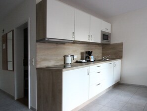 A modern kitchen with white cabinets, a stainless steel sink, and a microwave.
