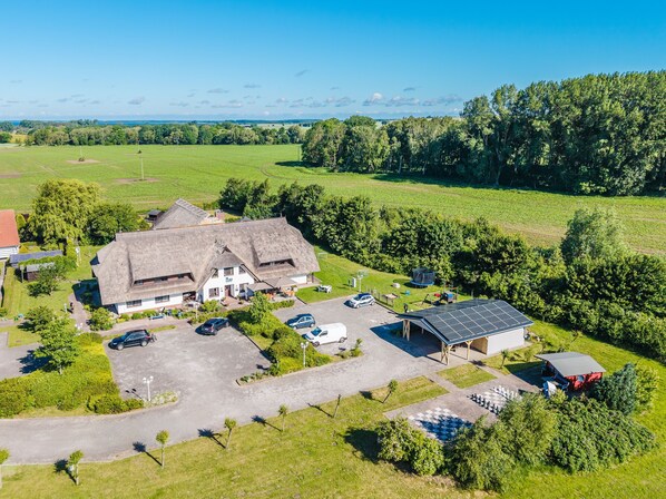 A large building with a thatched roof, surrounded by a parking area and a solar panel installation.