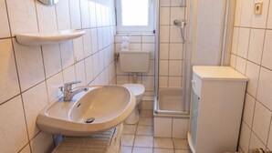 Et badeværelse med vask, toilet og bruser.