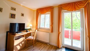 A room with a desk, chair, television, and a window with curtains. - 206 - Hotel Dunenschloss (Karlshagen)