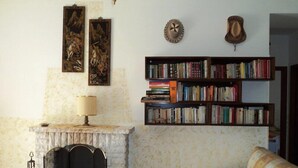 Ein Wohnzimmer mit Kamin, Bücherregal und einer Couch.