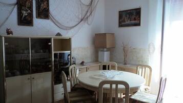 Zona pranzo con tavolo rotondo, sedie, un armadietto e una lampada a parete.