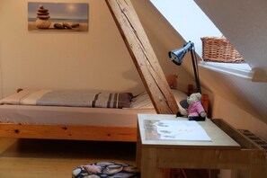 A cozy attic bedroom with a sloped ceiling, a wooden bed, a small desk with a lamp, and a teddy bear.
