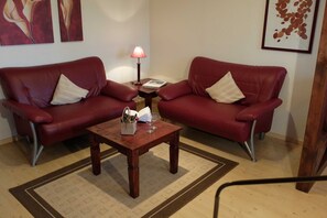 A room with two red leather sofas, a wooden coffee table, and a small table with a lamp and a book.