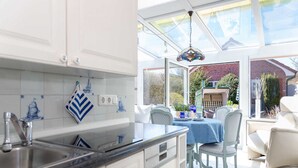 A kitchen with white cabinets, a sink, and a dining area with a table and chairs.