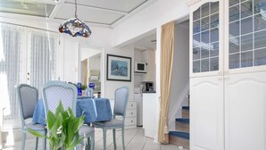 A bright room with a dining table, chairs, and a potted plant. There is a staircase leading to another level.
