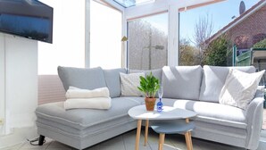 A modern living room with a grey sectional sofa, a small round table, and a potted plant.
