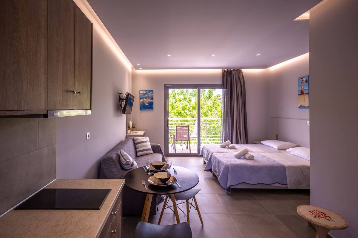 Una habitación moderna con comedor, sofá, cama y vistas a zonas verdes.