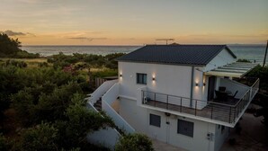 A modern two-story house with a balcony, located near a body of water.
