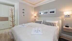 Een hotelkamer met een net opgemaakt bed, een kledingkast, een kapstok en wandlampen.