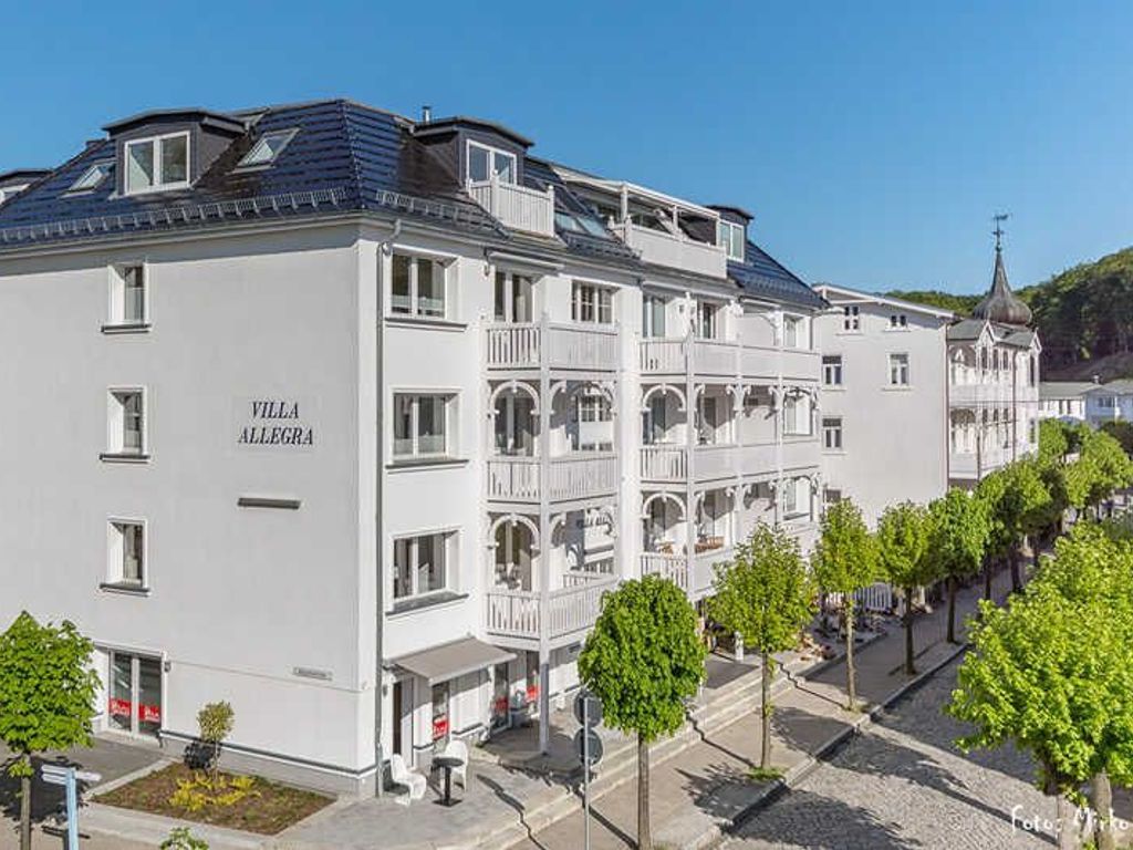 Un hôtel à plusieurs étages doté de balcons, un ciel dégagé et une église en arrière-plan.