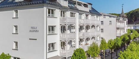 A multi-story hotel with balconies, a clear sky, and a church in the background.