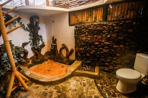 A bathroom with a stone wall, a bamboo ladder, a stone basin, and a toilet. - Sayang Mama Inn (Gili Air)