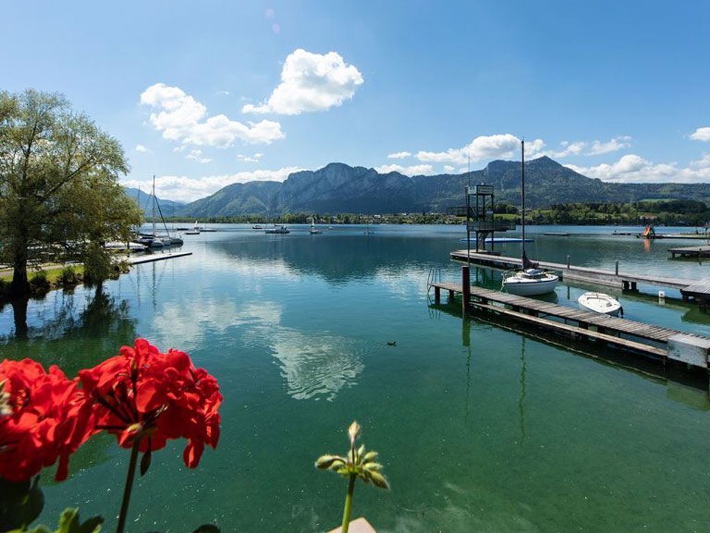 Un lac avec des bateaux, un quai et des montagnes en arrière-plan.