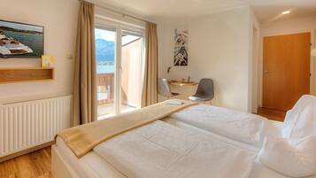 A hotel room with a bed, a desk, a chair, a window with a view, and a door.