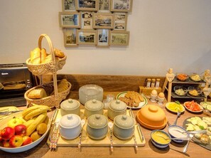 Un bufé de desayuno con pan, frutas y diversos platos.