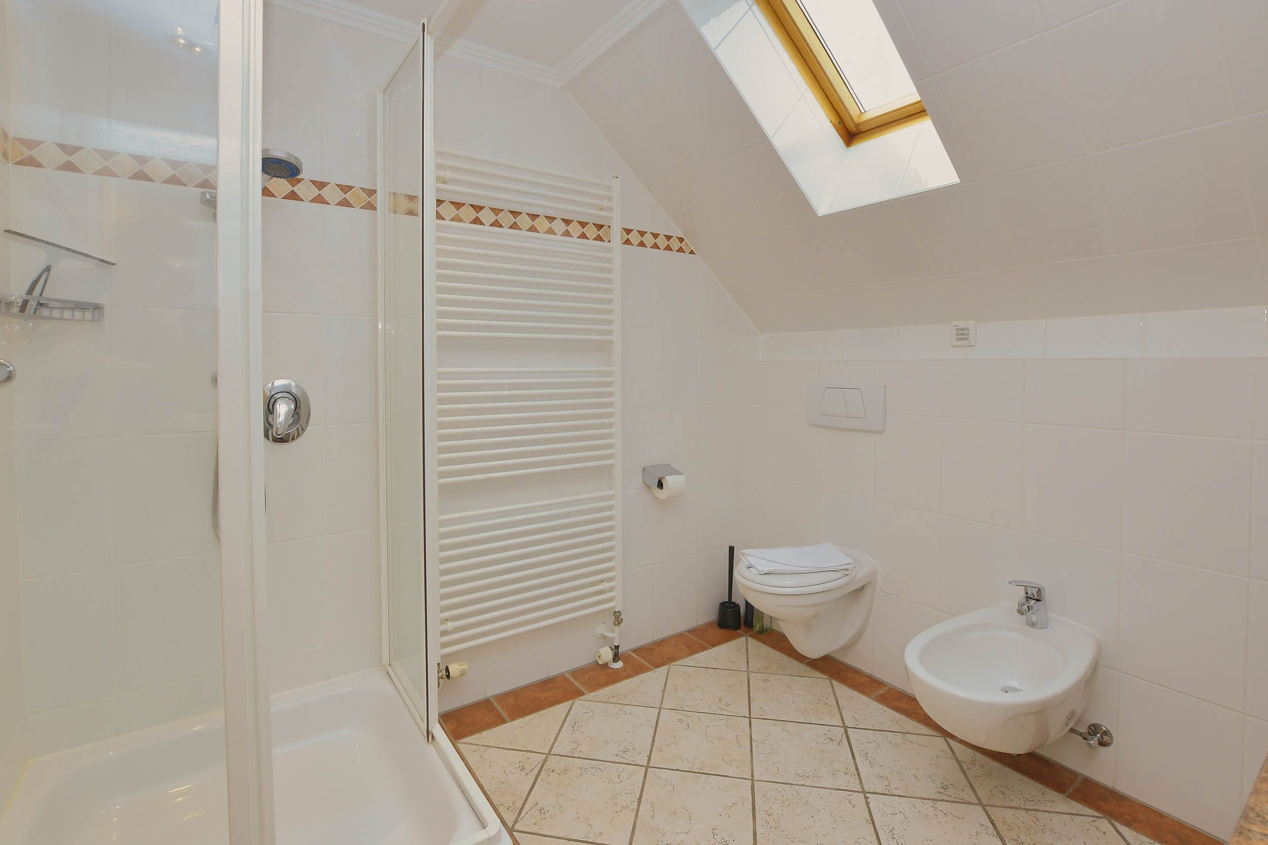 Une salle de bain avec une douche à parois de verre, un bidet et des toilettes.