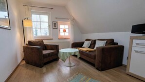 Un salon confortable avec un canapé, une petite table ronde et un téléviseur.