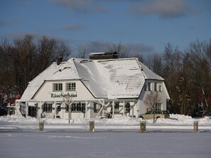 Een gebouw bedekt met sneeuw, met een bord waarop 'Räucheraus' staat.