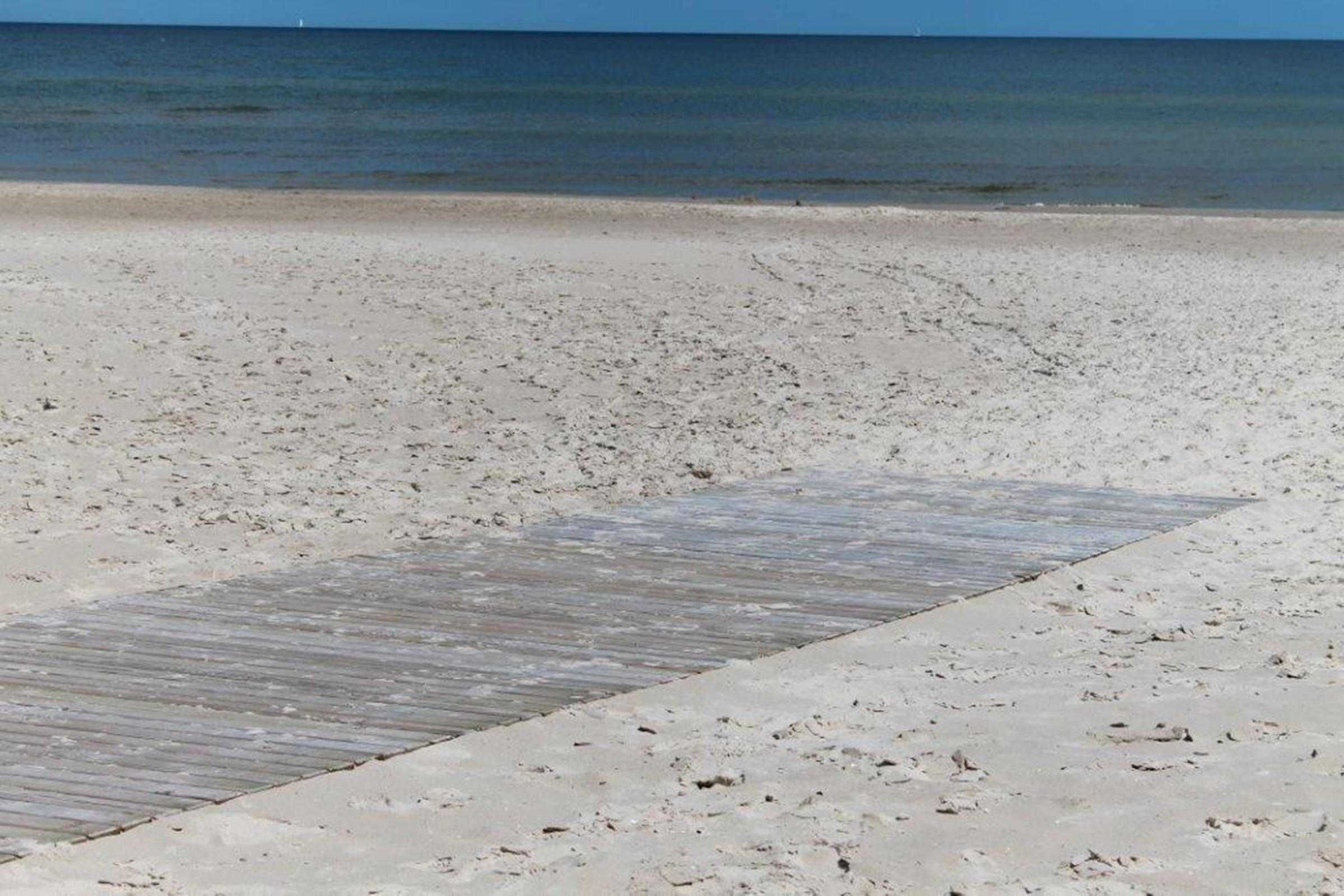 A beach with a wooden walkway leading to the water.