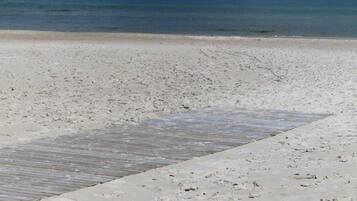 A beach with a wooden walkway leading to the water.