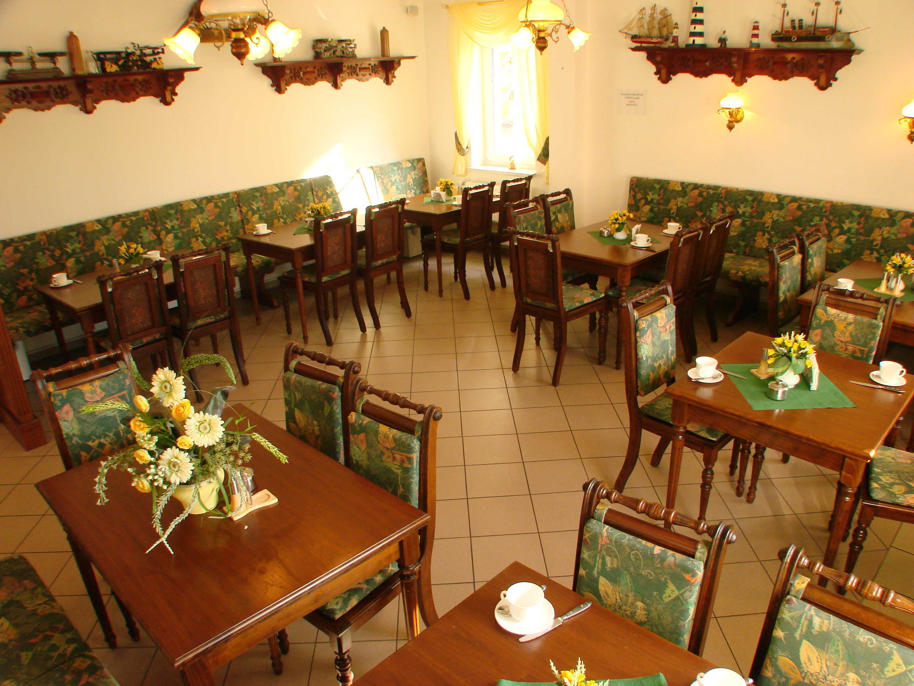 Un comedor con mesas y sillas de madera, centros de mesa con flores y decoración de pared con temática náutica.
