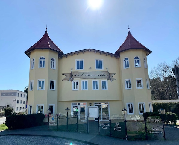 A two-story building with a sign reading "Hotel Dimenschloss".