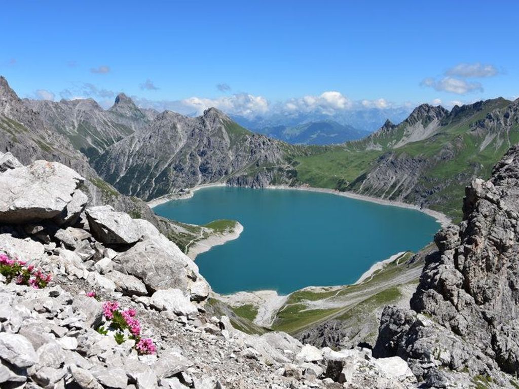 Un paisaje montañoso con un lago, terreno rocoso y vegetación escasa.