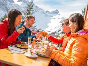 Un groupe de personnes déjeunant en plein air, avec une montagne en toile de fond.