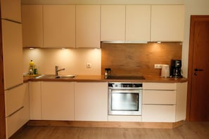 A compact kitchen with a built-in oven, a sink, and a coffee maker.