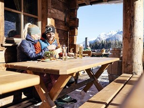 Une cabane en bois avec une table dressée pour deux personnes, une vue sur la montagne et un paysage enneigé.