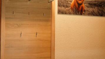 A wooden wardrobe with a bench, a wall-mounted heater, and a highland cow picture.