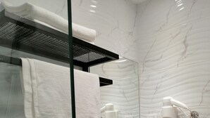 Un baño moderno con cabina de ducha de vidrio, un lavabo blanco y un inodoro.