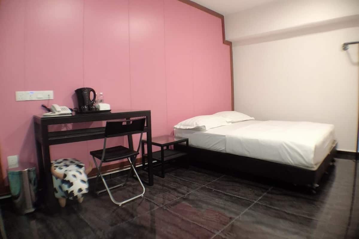 A small, compact room with a bed, a desk, and a chair.