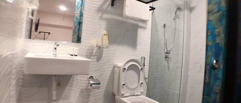 A bathroom with a toilet, sink, and shower.