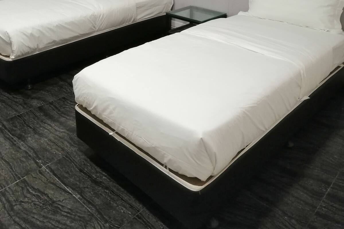 A room with two single beds, a glass table, and a patterned wall.