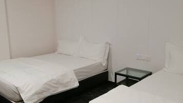 Une chambre d’hôtel avec deux lits, une petite table et une prise électrique au mur.