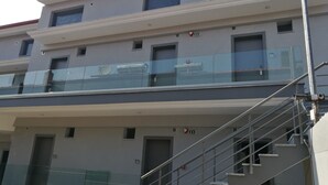 A multi-story building with a glass balcony on the second floor, metal railings, and a staircase leading to the upper floors. - 4-You Family 2 (Polygyros)