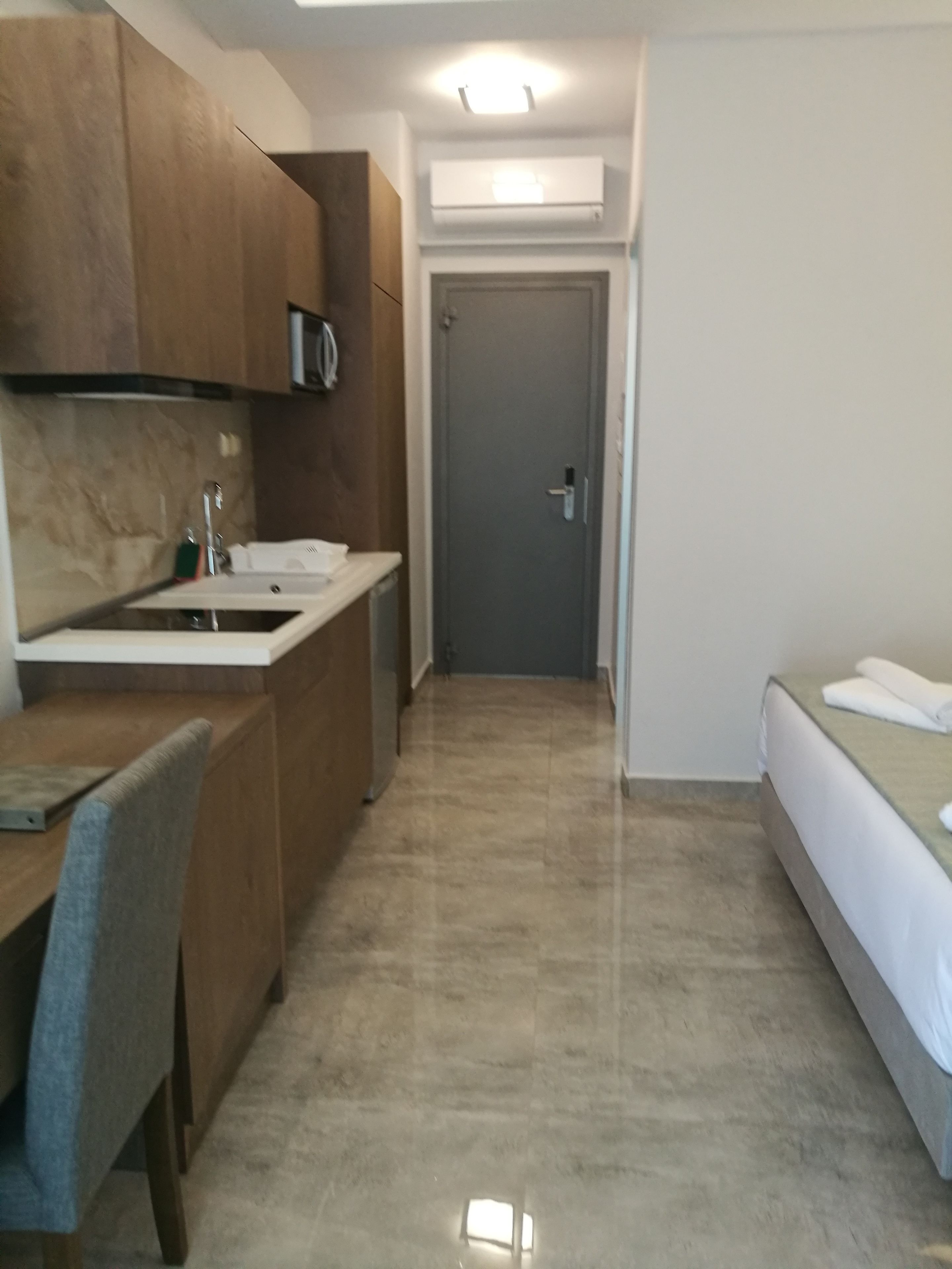 Habitación de hotel compacta con kitchenette, una cama individual y un escritorio pequeño.