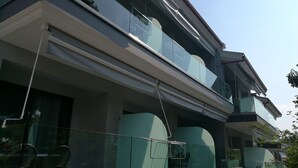 A modern building with a glass facade, a balcony with chairs, and a clear sky. - 4-You Family 2 (Polygyros)