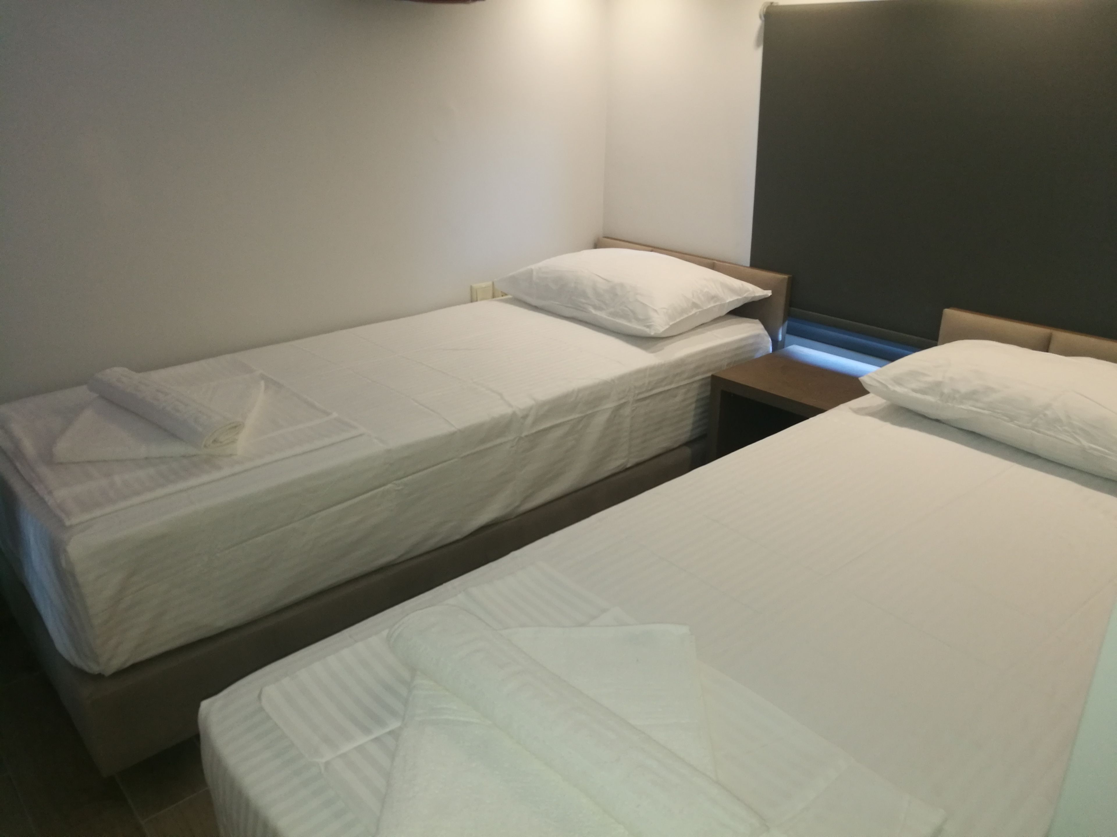 A hotel room with two single beds, each with a pillow and a neatly folded towel.