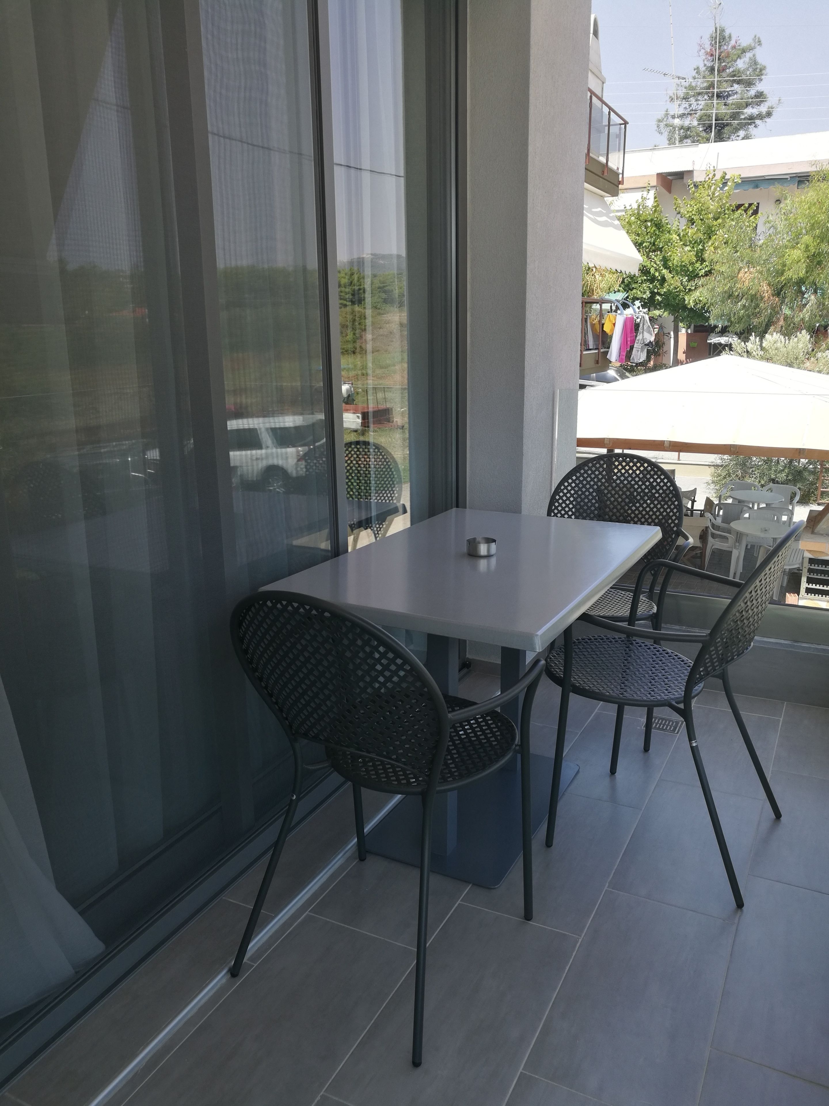A patio with a table and chairs, large windows, and a view of the outside.