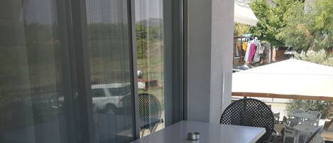 A patio with a table and chairs, large windows, and a view of the outside.
