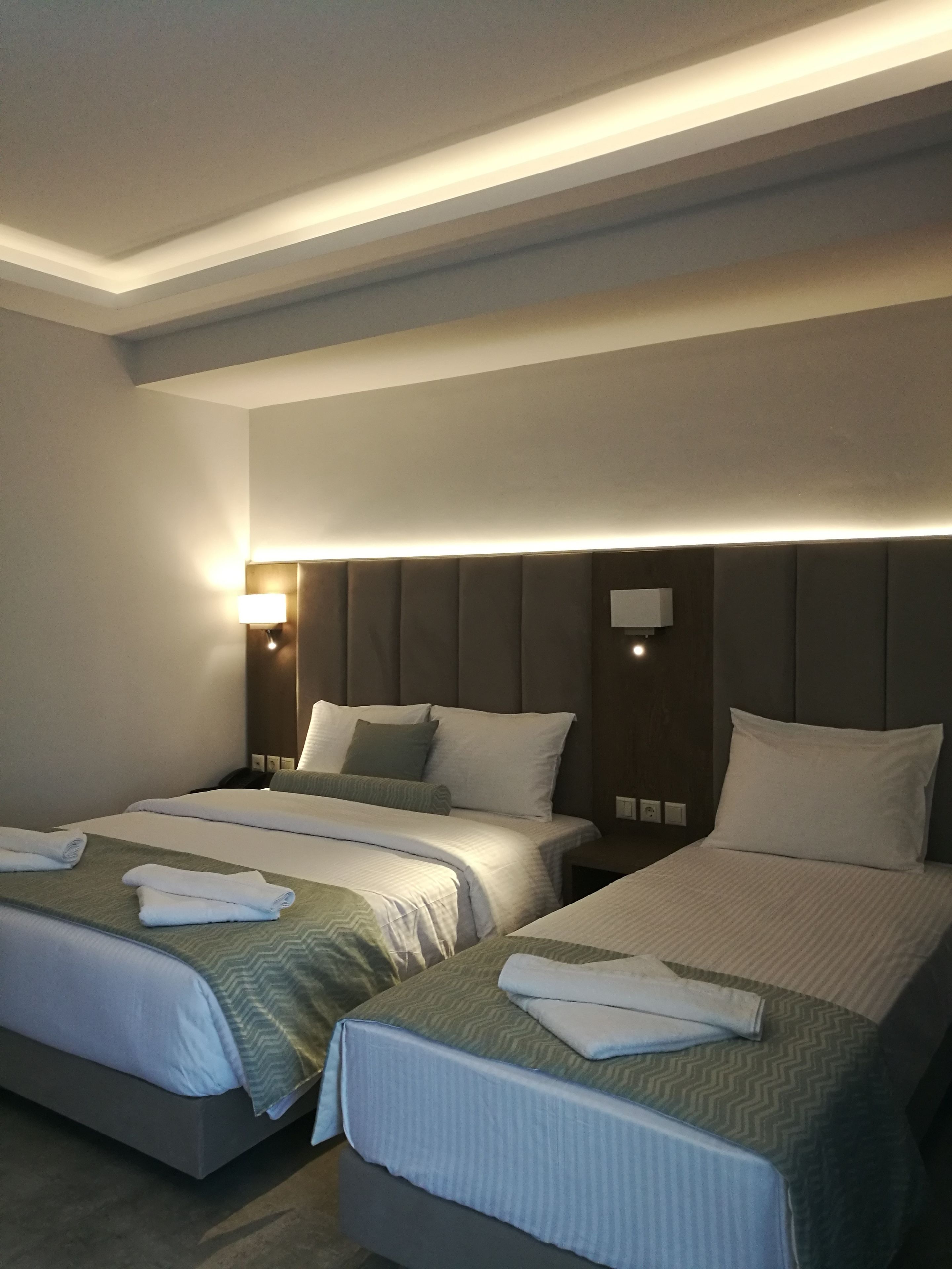 Habitació d'hotel amb dos llits, cadascun amb melic, taules de nit i làmpades.