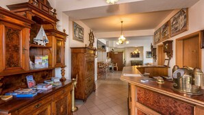 Un hall d’hôtel avec des meubles en bois, un comptoir d’accueil et un lustre.