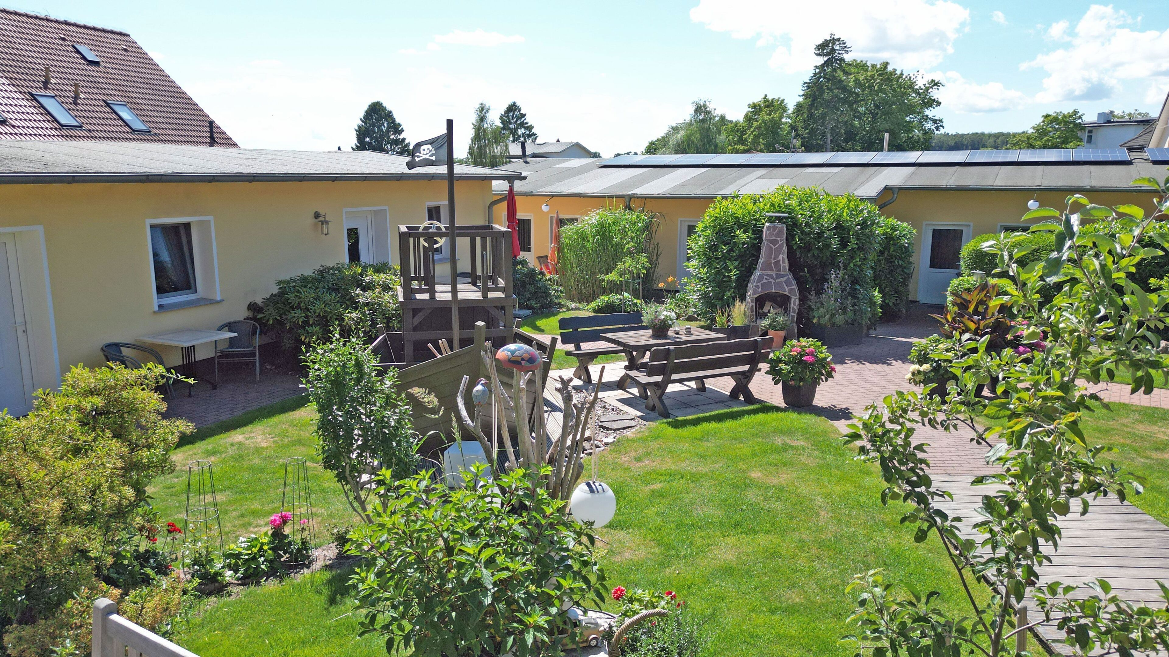 En innergård med en uteplats, utomhusmöbler, en steneldstad och en trädgård.