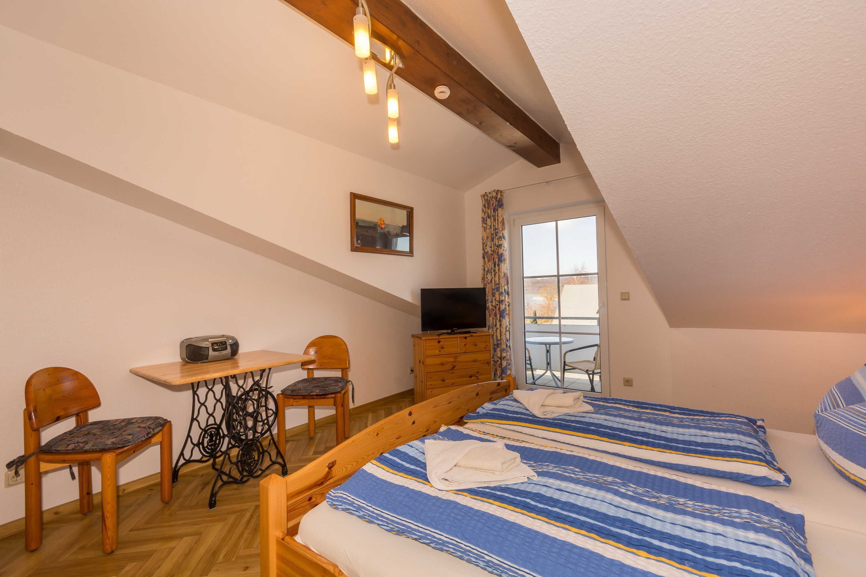 Una camera da letto con un letto in legno, una televisione, un tavolo con sedie e una finestra con tende.