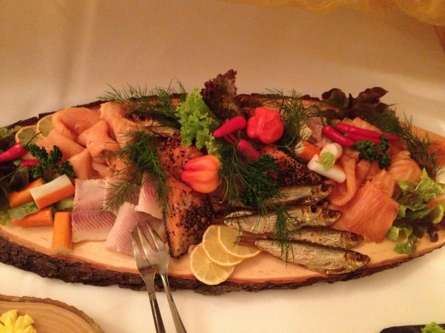 A wooden platter with various seafood, vegetables, and herbs.