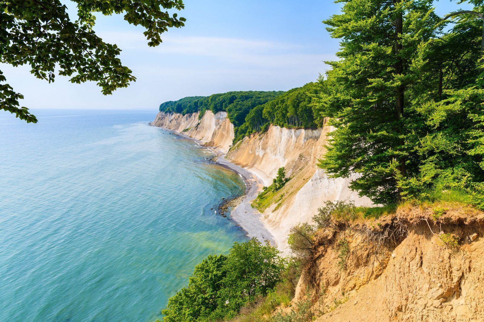 A coastal landscape with cliffs, a beach, and dense greenery.
